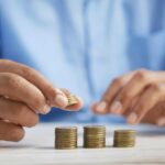 a man with blue shirt is budgeting and stacking coins